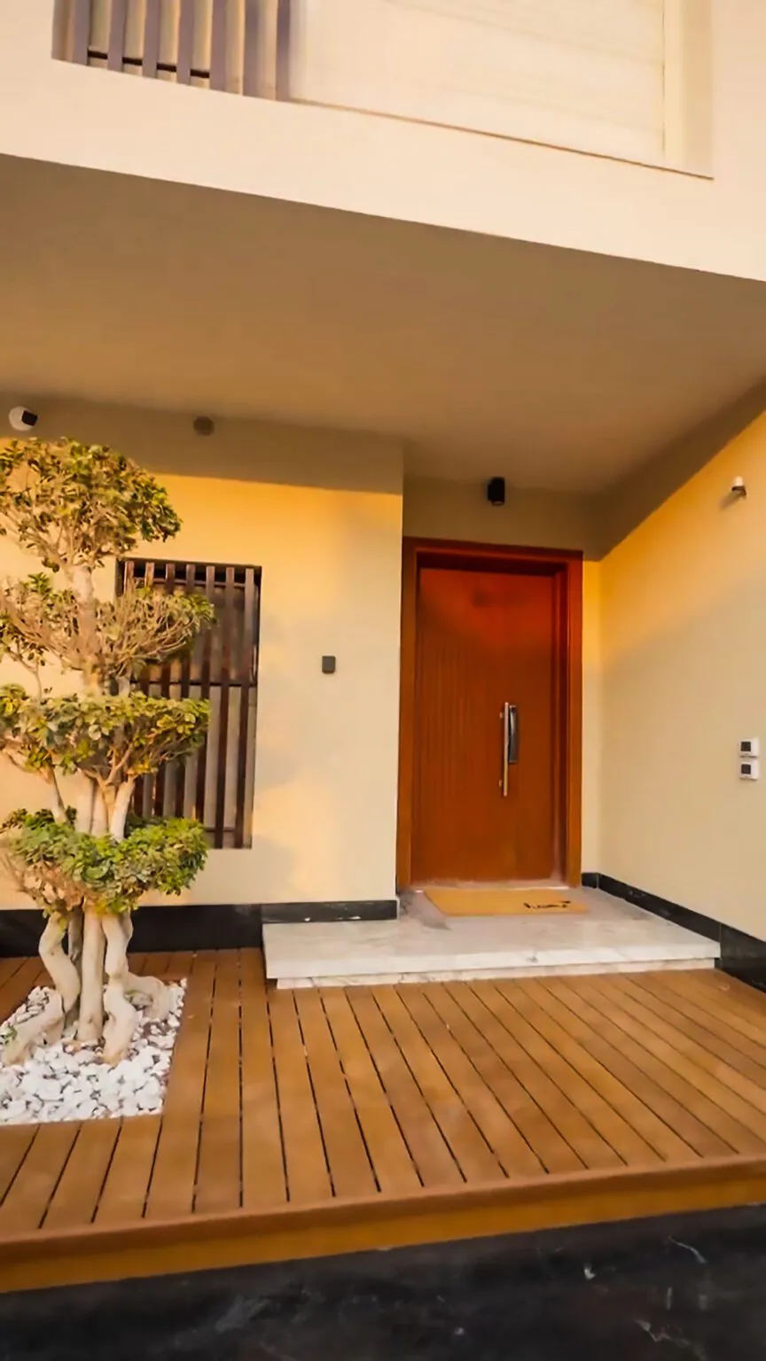 Modern home entrance with a large wooden door, accent lighting, and decorative plants from Consept Art's site work portfolio.