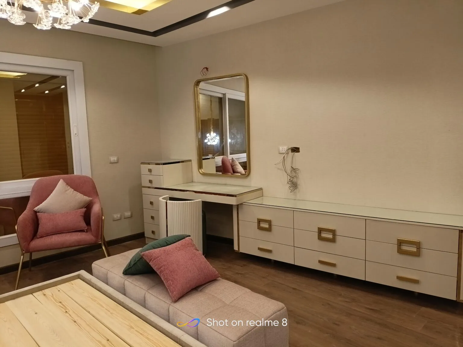 Cozy bedroom featuring a light wooden bed, patterned cushions, and a sleek dressing table.