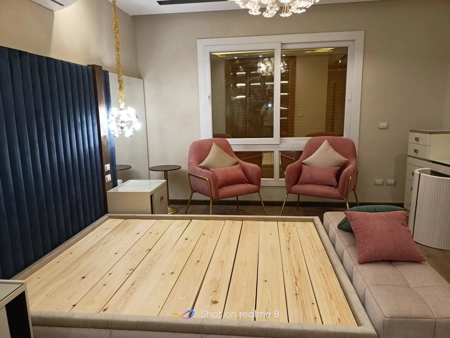 Stylish room with a blue fabric headboard, wooden furniture, and a neatly arranged seating area in New Cairo from Consept Art's site work portfolio.