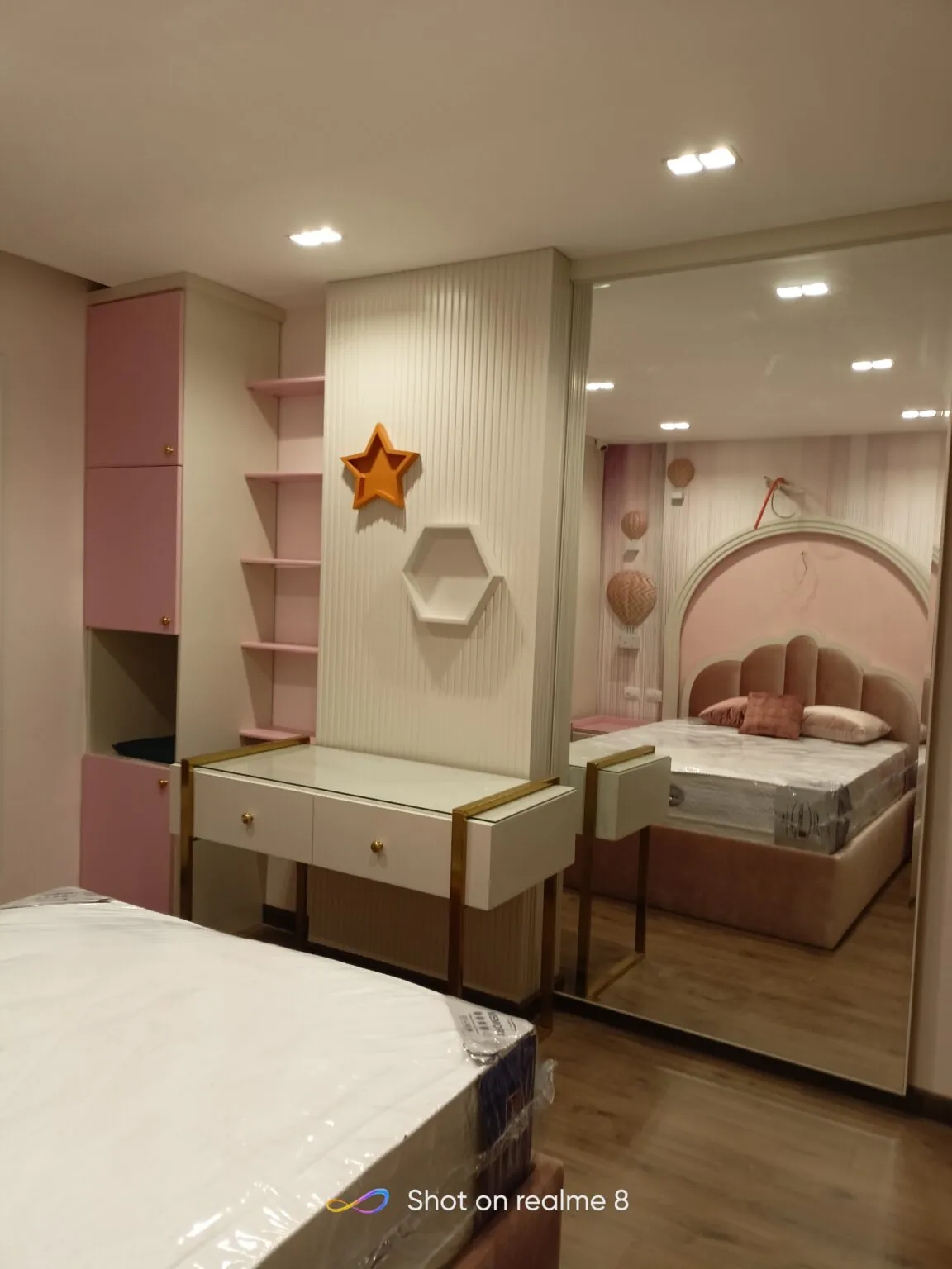 Chic children's bedroom with pink accents, a star-shaped decor piece, and a comfortable bed.