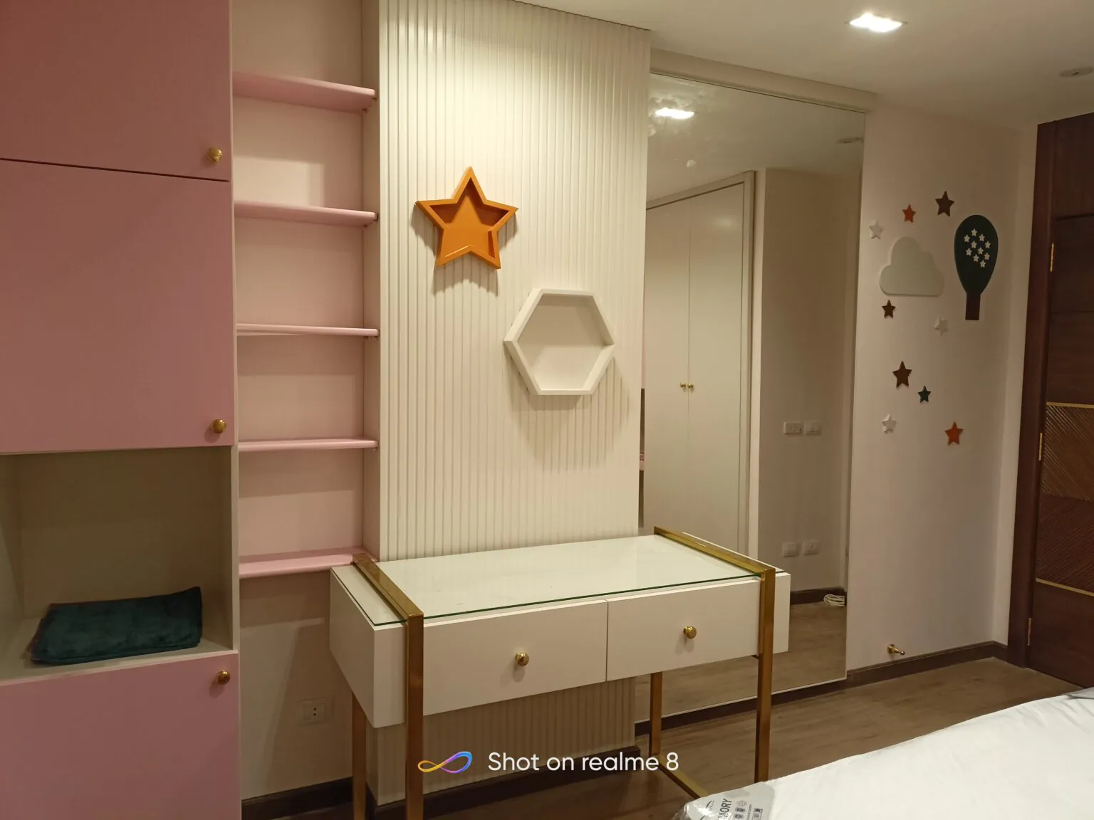 Modern bedroom with soft tones, a pink bed design, and a clean and organized layout.