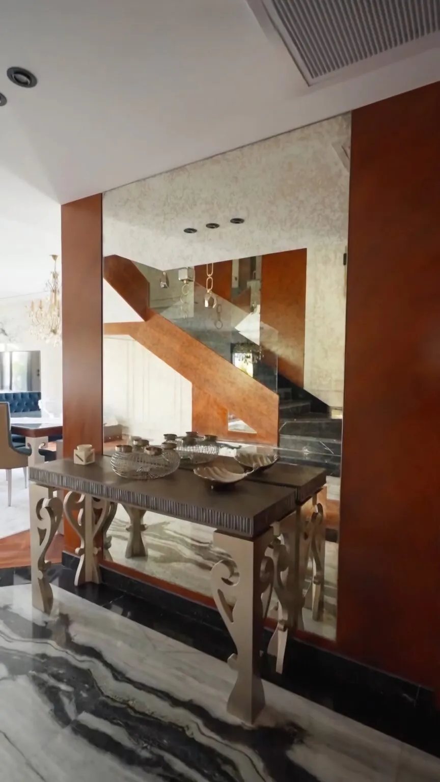 Elegant seating area with plush armchairs, a glass coffee table, and metallic gold accents on the walls in New Cairo.
