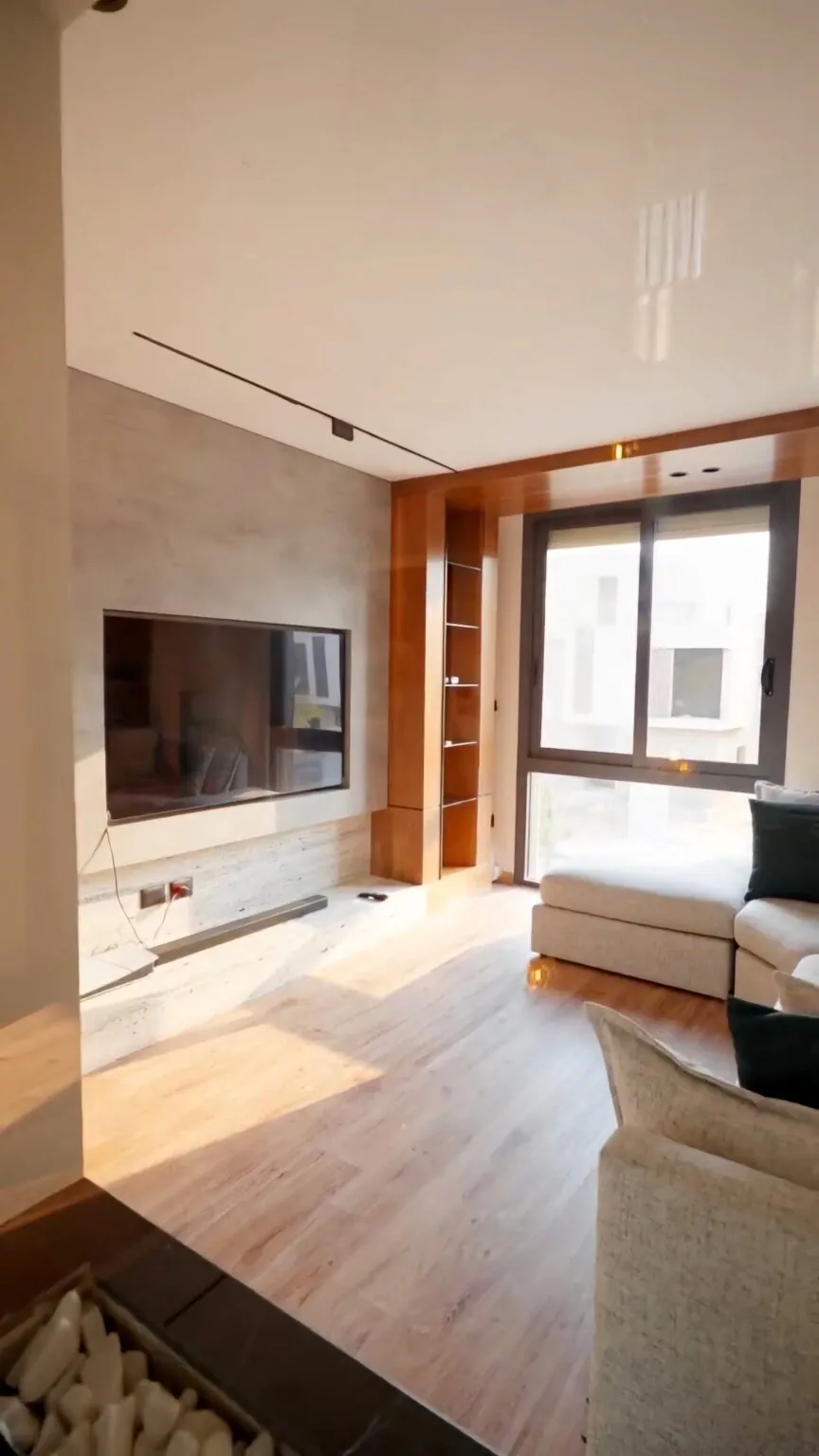 Modern living room with built-in wooden shelving, a mounted TV, and a comfortable seating arrangement in New Cairo from Consept Art's site work portfolio.