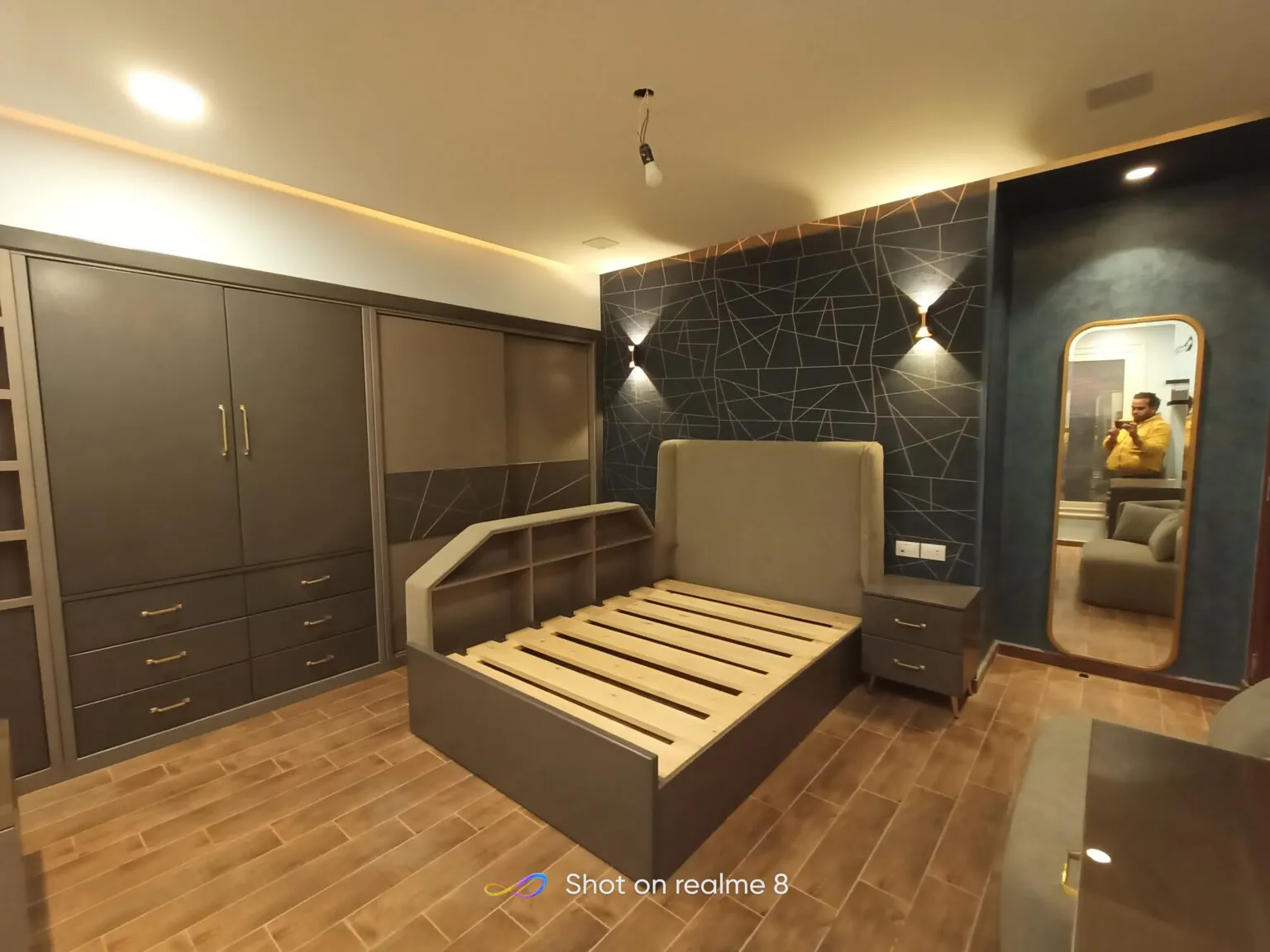 Elegant dressing room with wooden flooring, a striped bed design, and a combination of modern lighting fixtures in Cairo.