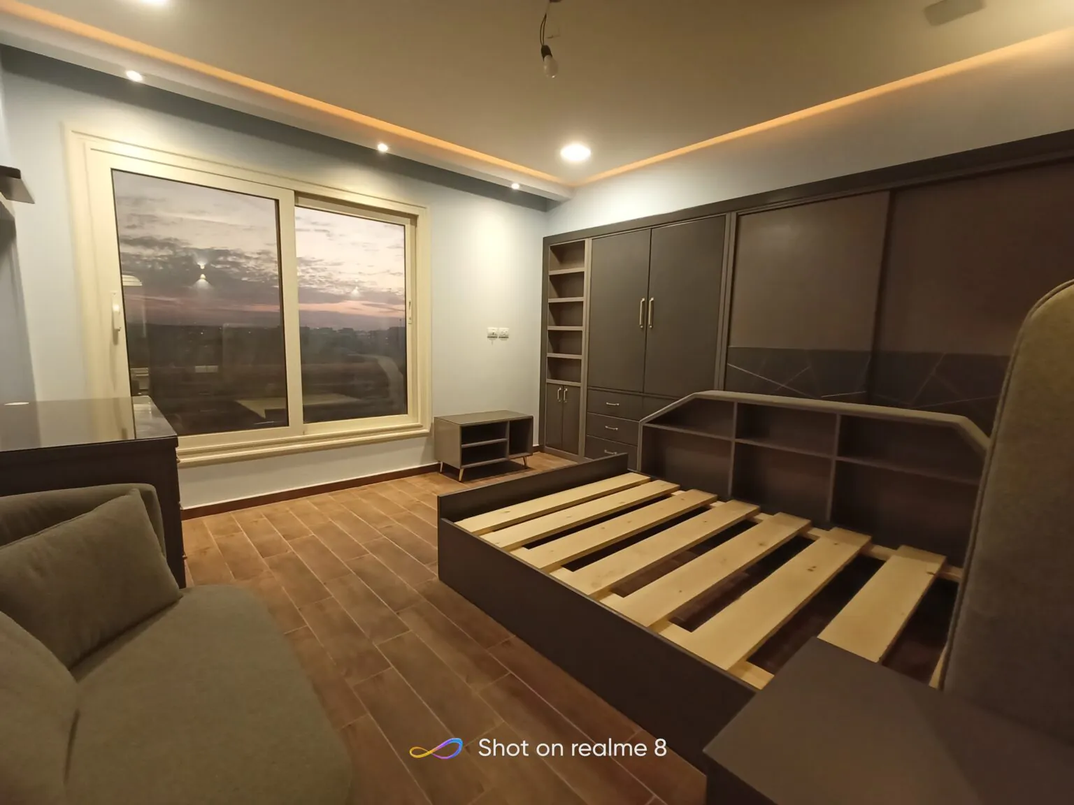 Elegant bedroom with wooden flooring, a striped bed design, and a combination of modern lighting fixtures.