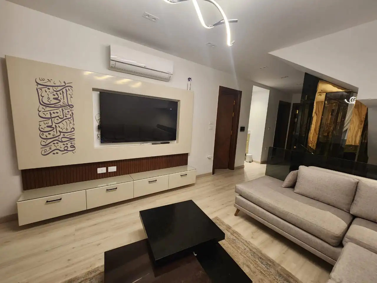 Contemporary living room featuring a sleek sectional sofa, a flat-screen TV, and ambient lighting.