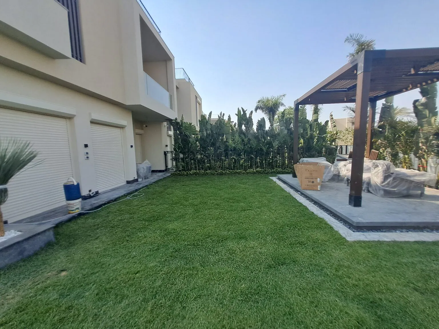 Large garden area with neatly trimmed grass, outdoor seating, and a stone patio.