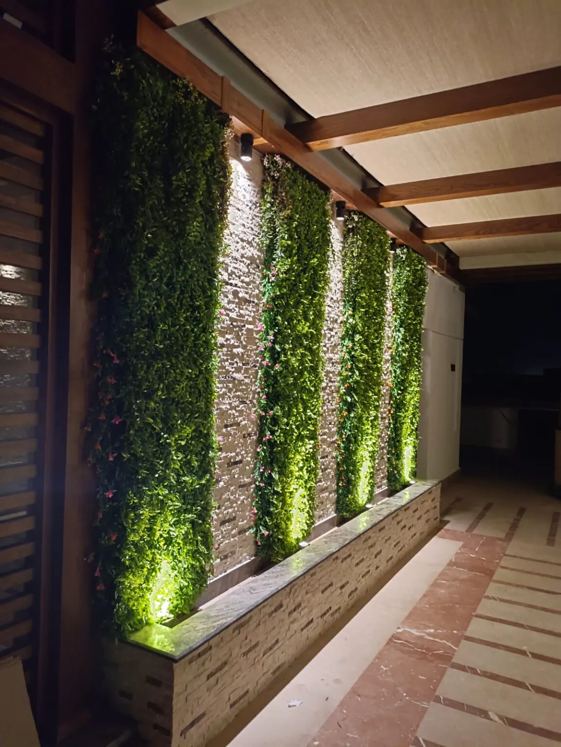 Charming garden pathway featuring illuminated vertical green walls and a rustic pergola.